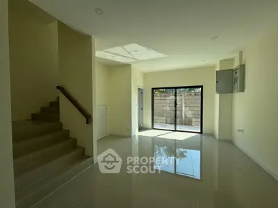 Spacious modern living room with large window and staircase, perfect for natural light lovers.