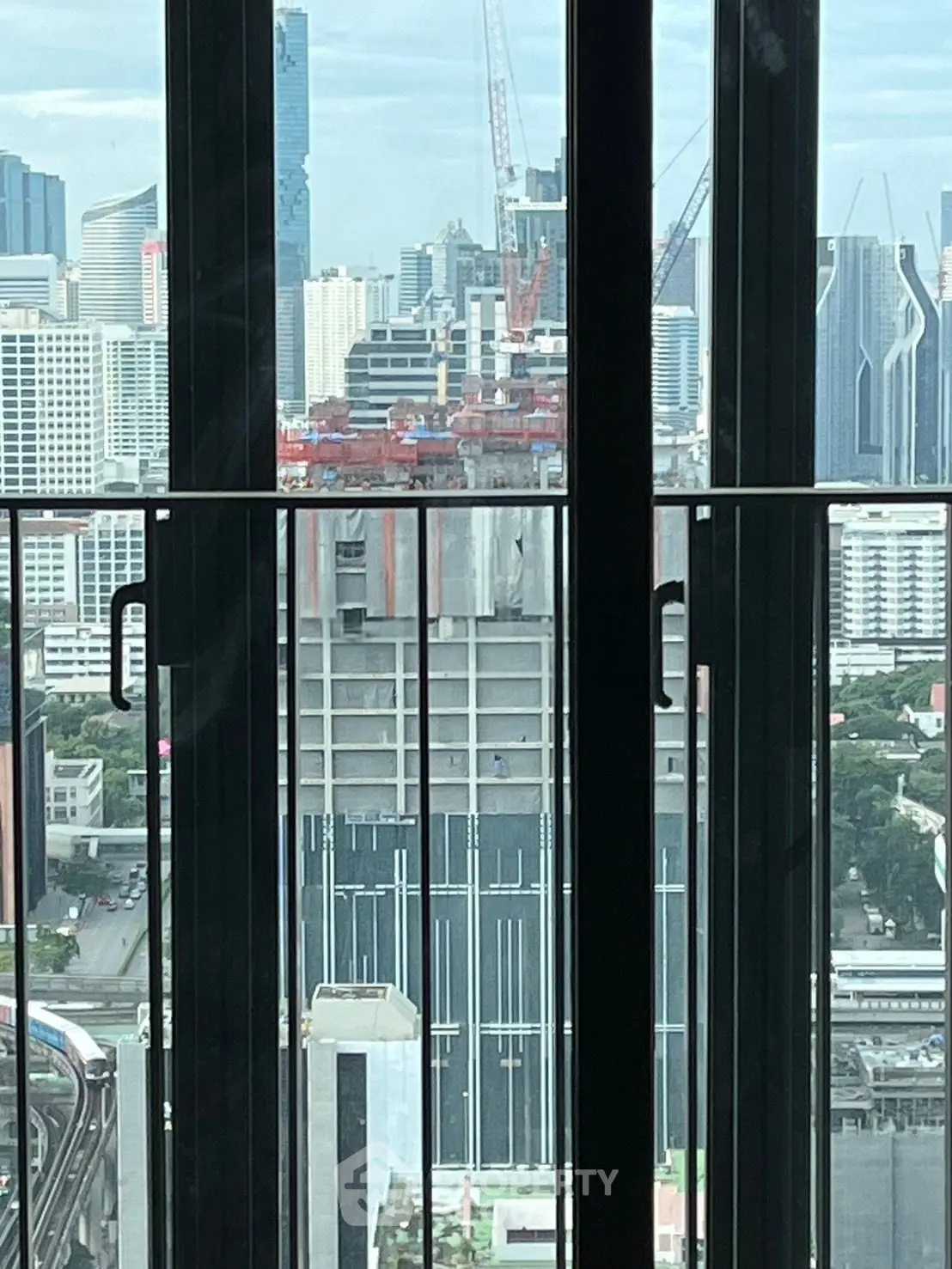 Stunning cityscape view from a high-rise balcony with modern skyscrapers and construction in the background.