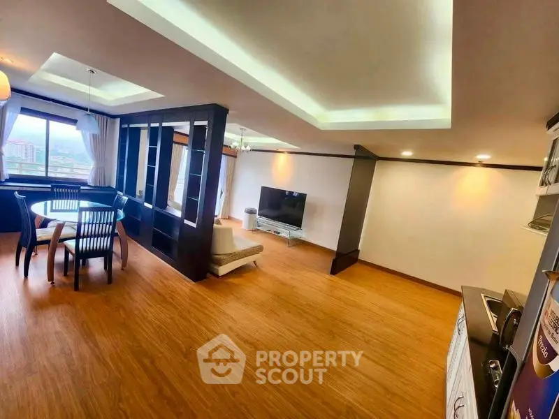 Spacious open-layout living room with dining area and modern decor, featuring large windows with city views.