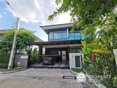 Modern two-story residence with expansive windows and a covered carport, surrounded by lush greenery in a serene neighborhood, offering a blend of luxury and comfort.