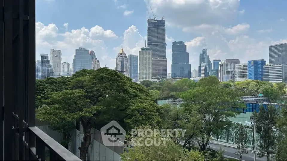 Stunning cityscape view from a balcony overlooking lush greenery and skyscrapers under a bright blue sky.
