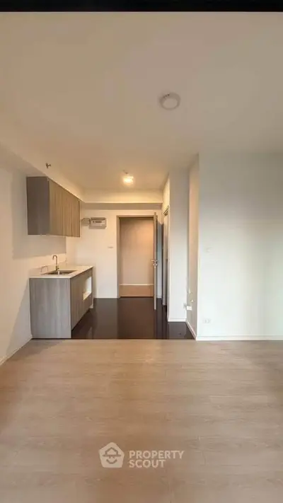 Modern open-plan kitchen with sleek cabinetry and wooden flooring in a bright apartment.