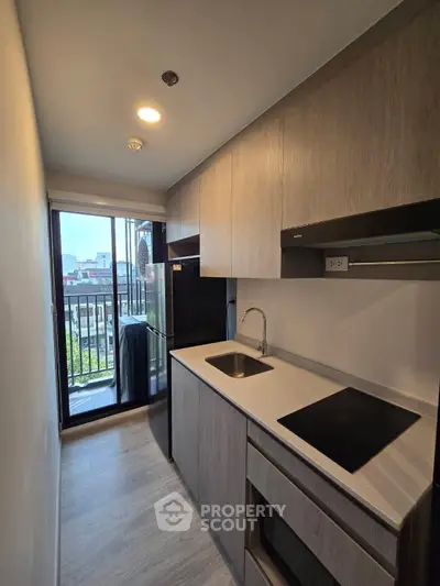 Modern kitchen with sleek cabinetry and balcony view in urban apartment