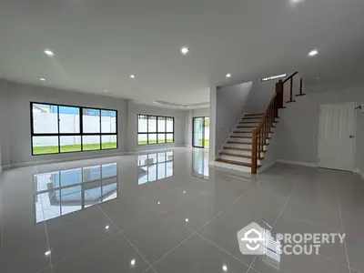 Spacious modern living room with glossy tile flooring and elegant staircase