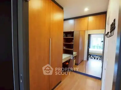 Spacious walk-in closet with wooden cabinetry and mirrored doors in modern apartment.