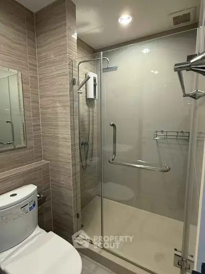 Modern bathroom with glass shower enclosure and sleek fixtures in a contemporary apartment.