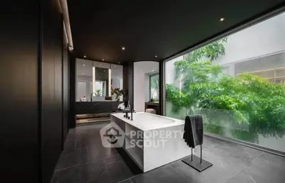 Luxurious modern bathroom with sleek design and large window overlooking lush greenery.