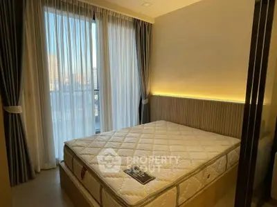 Cozy bedroom with large window and elegant curtains, featuring a comfortable mattress and ambient lighting.