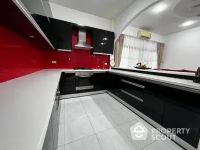 Modern kitchen with sleek black cabinets and vibrant red backsplash