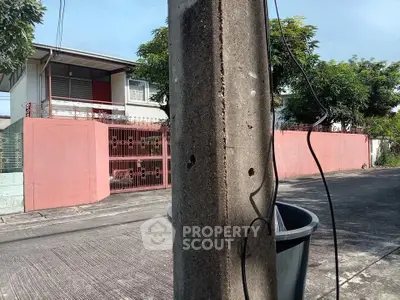 Charming suburban house with red gate and lush greenery, perfect for family living.