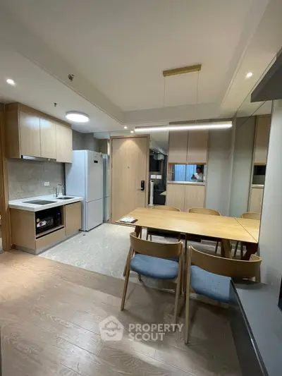 Modern kitchen and dining area with sleek wooden cabinetry and contemporary furniture.