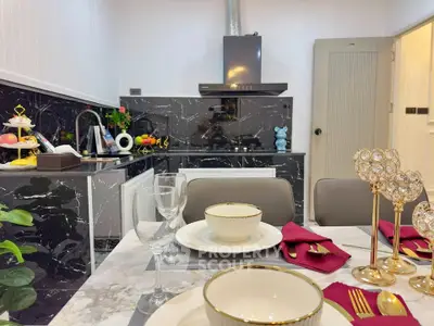 Luxurious kitchen with elegant dining setup and modern black marble countertops.