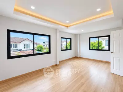 Spacious empty room with large windows and wooden flooring, perfect for customization.