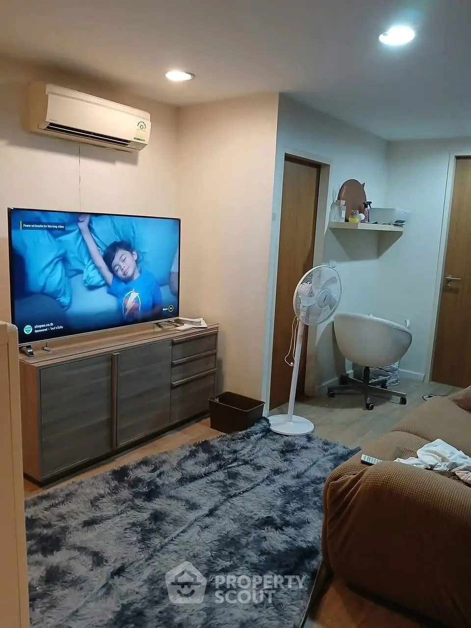 Cozy living room with modern decor, featuring a large TV, air conditioning, and stylish furniture.