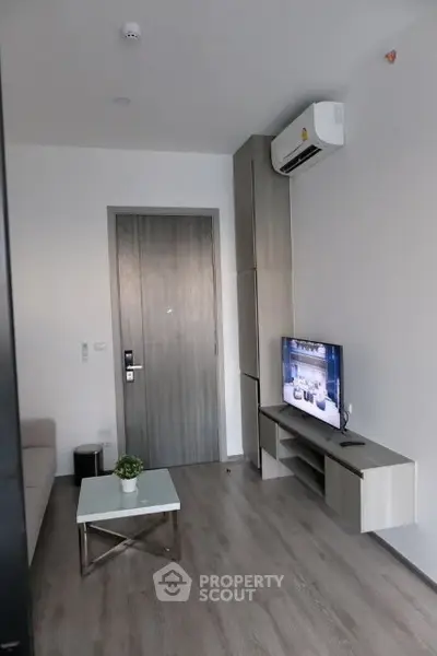 Modern living room with sleek design, featuring a wall-mounted TV and air conditioning unit.