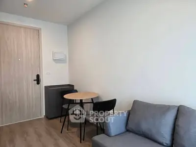 Modern living room with cozy gray sofa and compact dining area in a stylish apartment.