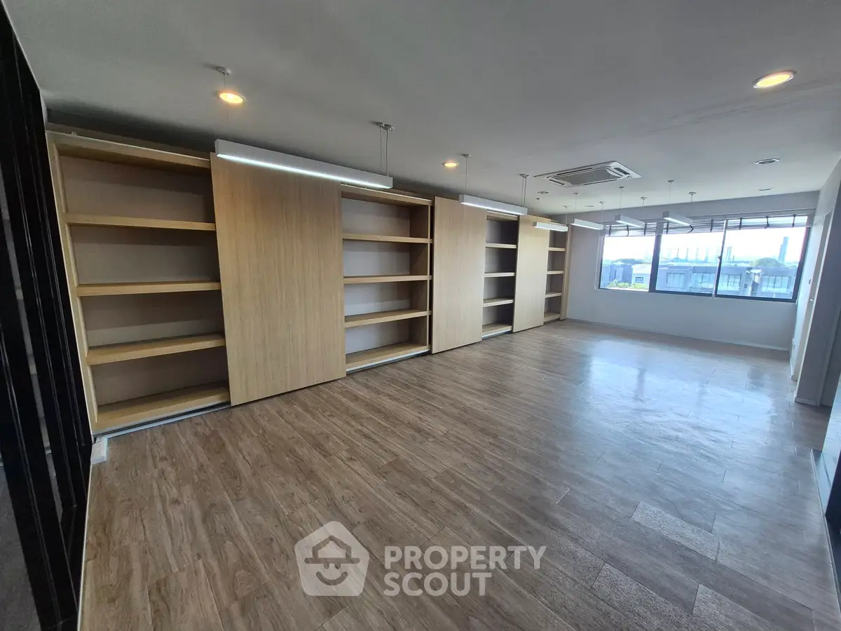 Spacious modern study room with wooden flooring and built-in shelves.