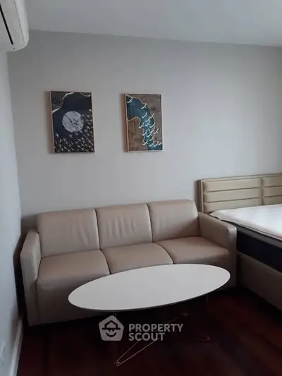 Modern living room with beige sofa, stylish artwork, and sleek wooden flooring.