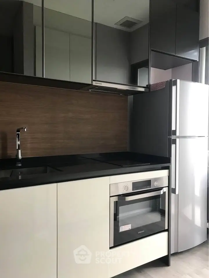 Modern kitchen with sleek cabinetry, built-in oven, and stainless steel fridge in a stylish apartment.