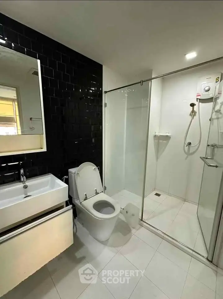 Modern bathroom with sleek black tiles and glass shower enclosure