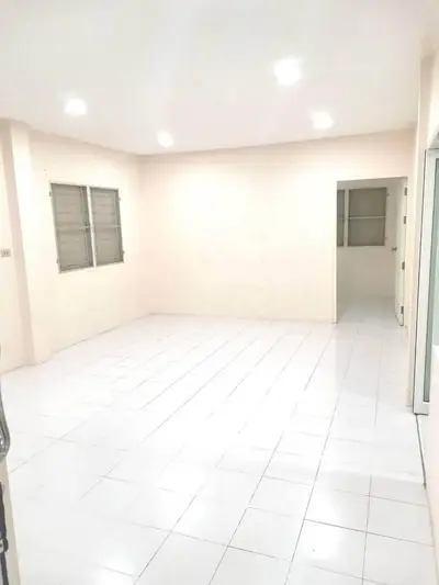 Spacious unfurnished room with white tiled flooring and ample natural light.