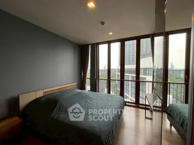 Modern bedroom with large windows offering city view, featuring sleek design and natural light.