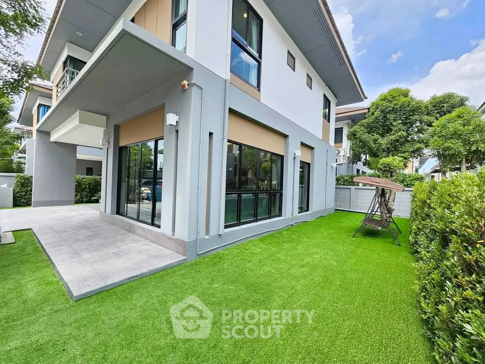 Modern two-story house with lush green lawn and large windows