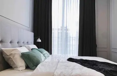 Elegant bedroom with plush bedding and large window for natural light
