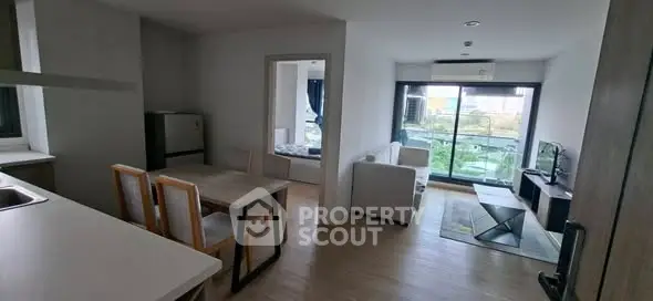 Modern open-plan living room with dining area and balcony view in a stylish apartment.