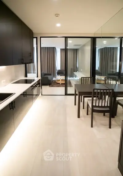 Modern open-layout kitchen with sleek black cabinets and dining area leading to a cozy living room.