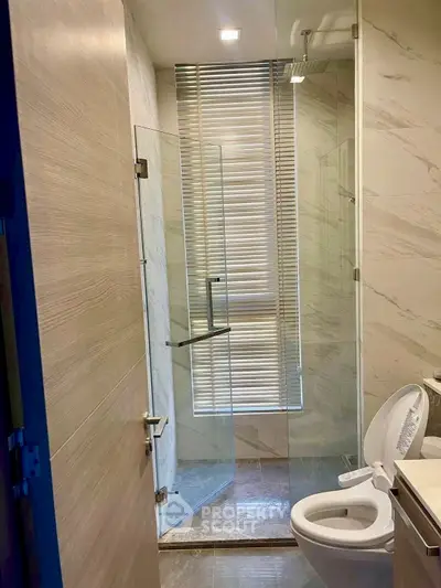 Modern bathroom with glass shower and marble walls