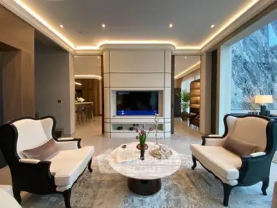 Luxurious living room with elegant seating and modern decor, featuring a large TV and ambient lighting.