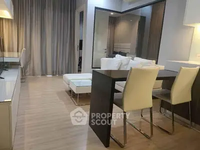 Modern living room with sleek furniture and open layout, featuring elegant dining area and cozy seating.