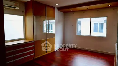 Spacious bedroom with wooden floors and built-in wardrobe, featuring large windows for natural light.
