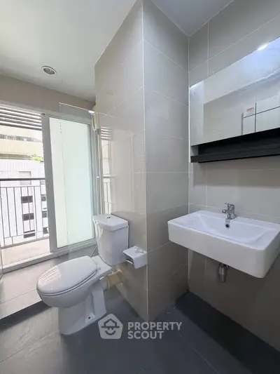 Modern bathroom with sleek fixtures and balcony view in a contemporary apartment.