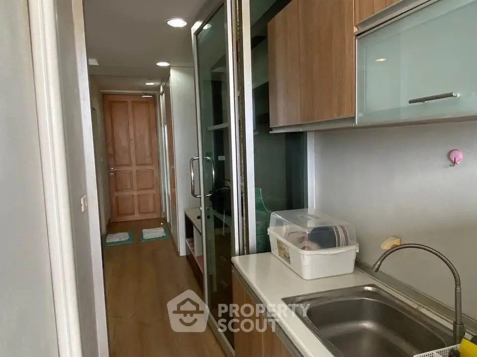 Compact kitchen with wooden cabinets and glass sliding doors in modern apartment