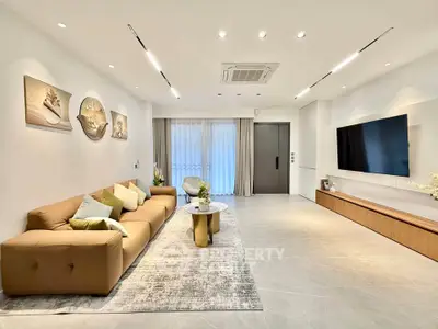 Modern living room with stylish decor, large sofa, and wall-mounted TV in a bright, spacious interior.