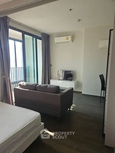 Modern studio apartment with balcony, featuring sleek furniture and ample natural light.
