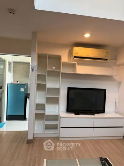 Modern living room with built-in shelves, TV, and air conditioning unit.