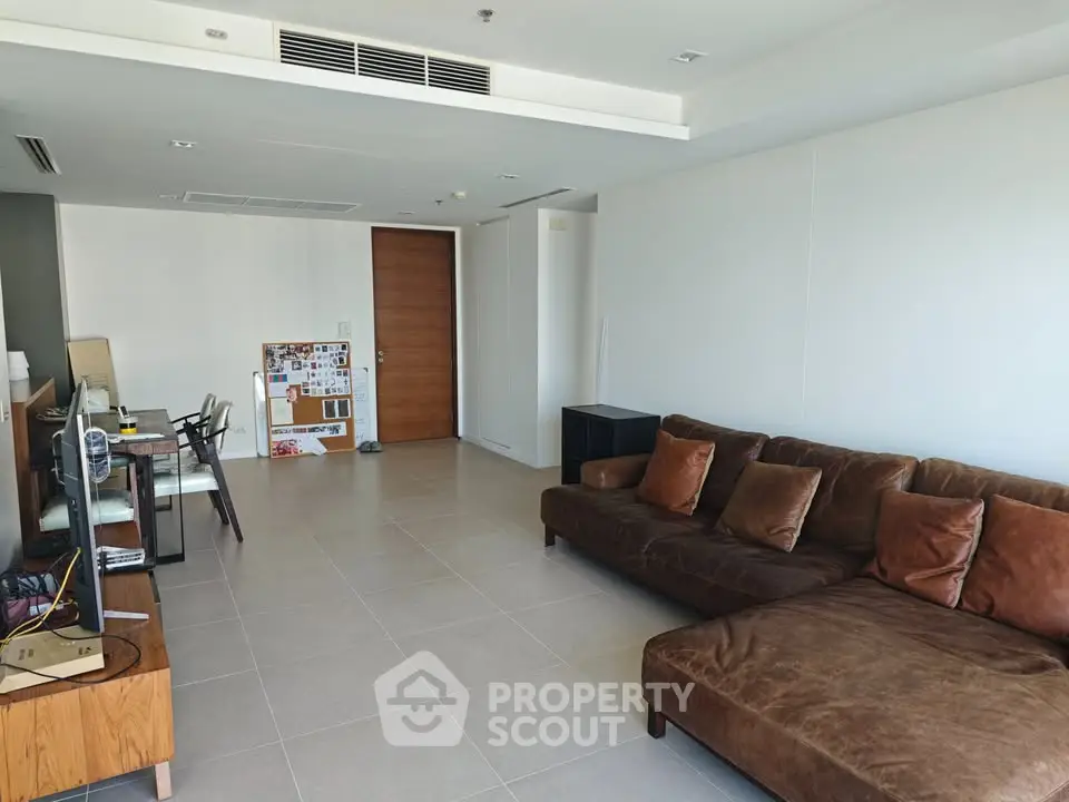 Spacious modern living room with brown sectional sofa and sleek tile flooring.