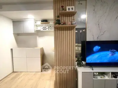 Modern living room with stylish decor and open layout, featuring a sleek TV setup and elegant shelving.