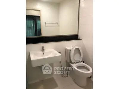 Modern bathroom with sleek white fixtures and large mirror