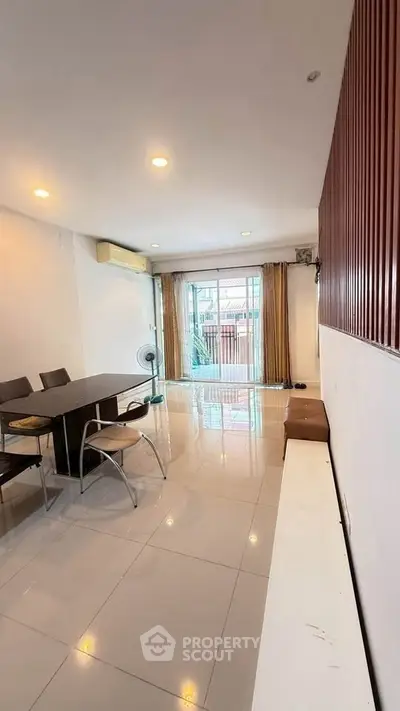 Spacious living room with modern dining set and large window for natural light.