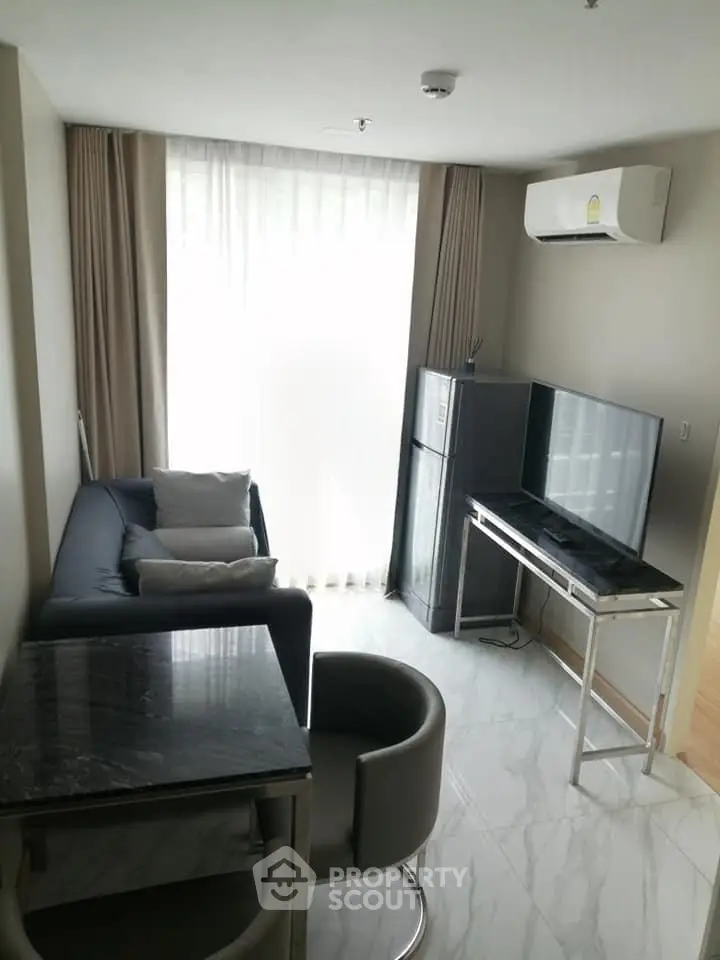 Modern living room with sleek furniture and natural light, featuring a compact layout and air conditioning.
