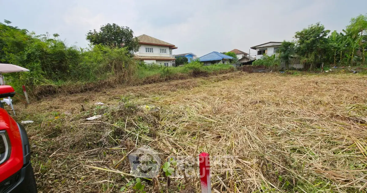 Vacant land plot with potential for development in a suburban area, surrounded by greenery and residential homes.