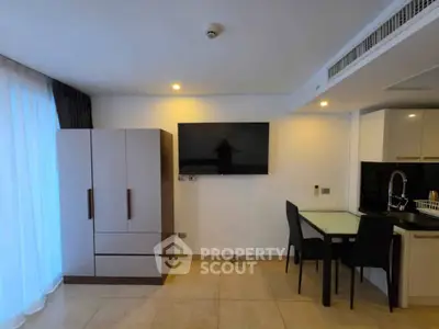 Modern living area with wall-mounted TV and dining space in stylish apartment.
