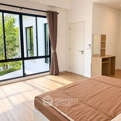 Spacious bedroom with large windows and modern decor, offering abundant natural light and a serene atmosphere.