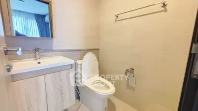 Modern bathroom with sleek fixtures and neutral tones, featuring a toilet and vanity sink.
