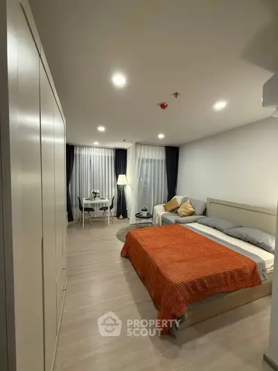 Modern bedroom with cozy decor and natural lighting, featuring a stylish bed and seating area.