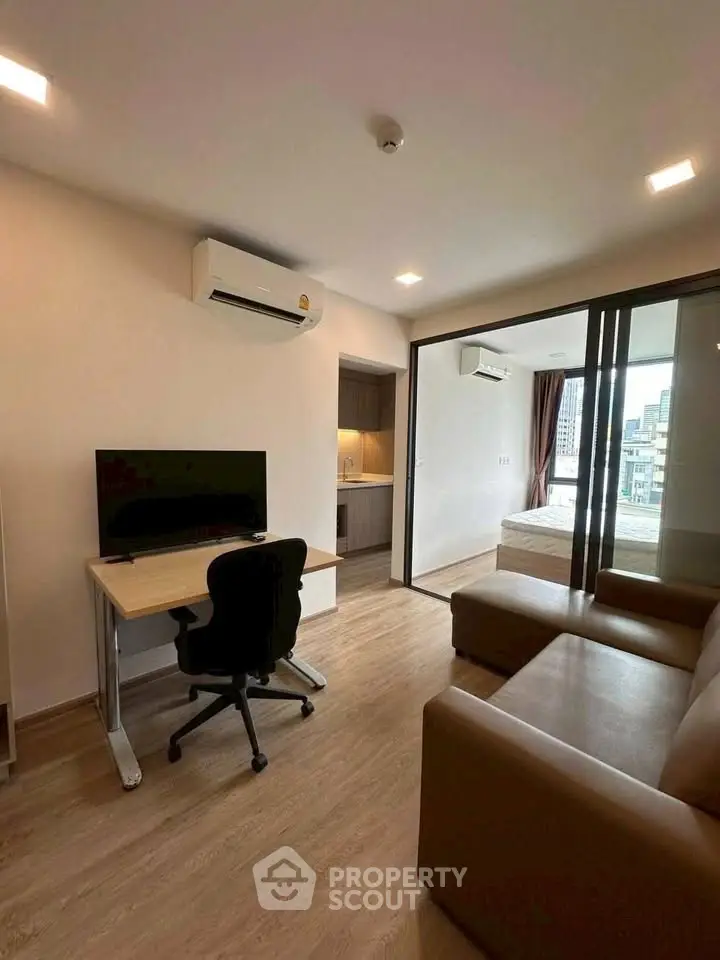 Modern apartment interior with cozy living room and study area, featuring sleek furniture and natural light.